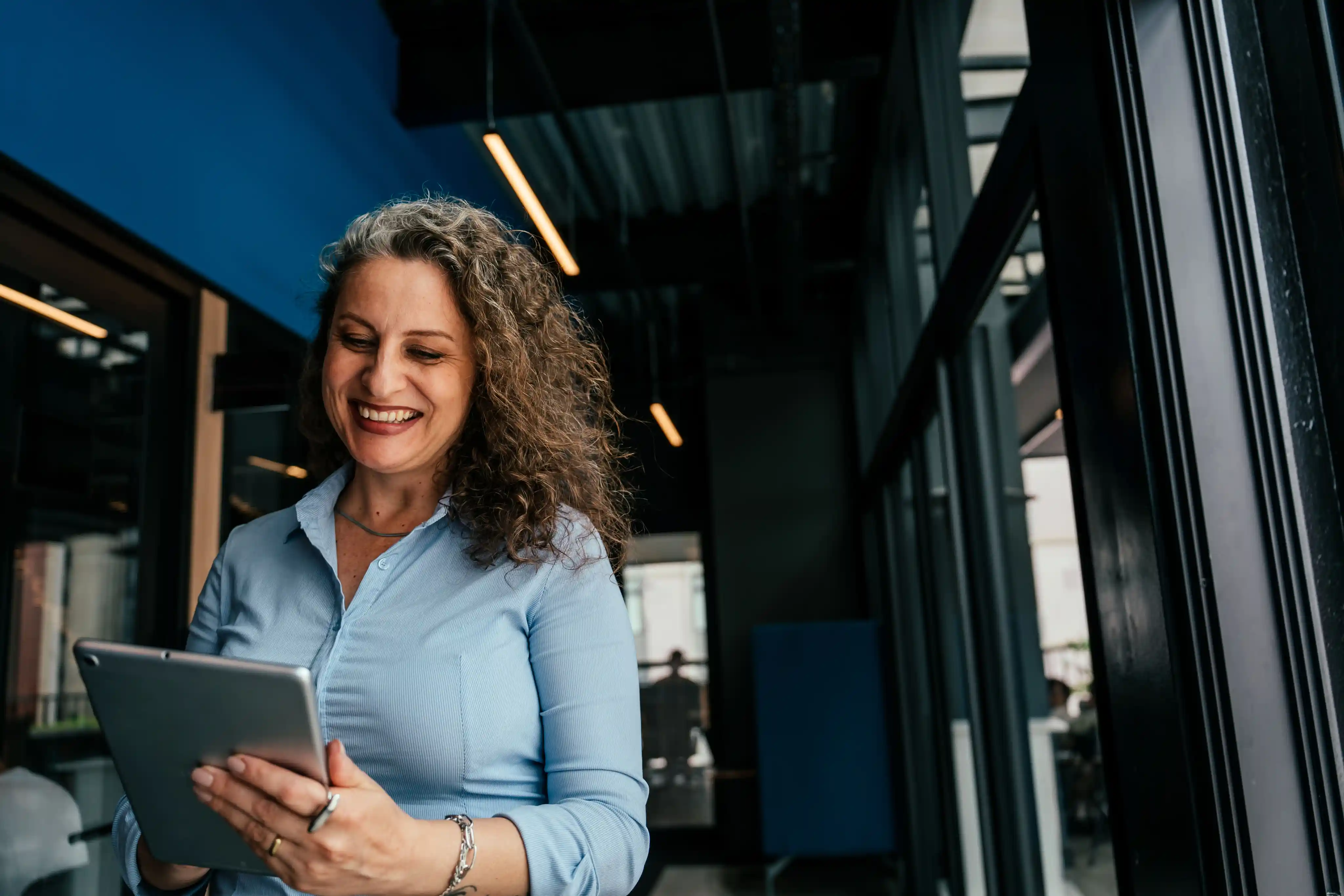 Smiling executive reviewing company performance on a tablet outside the office